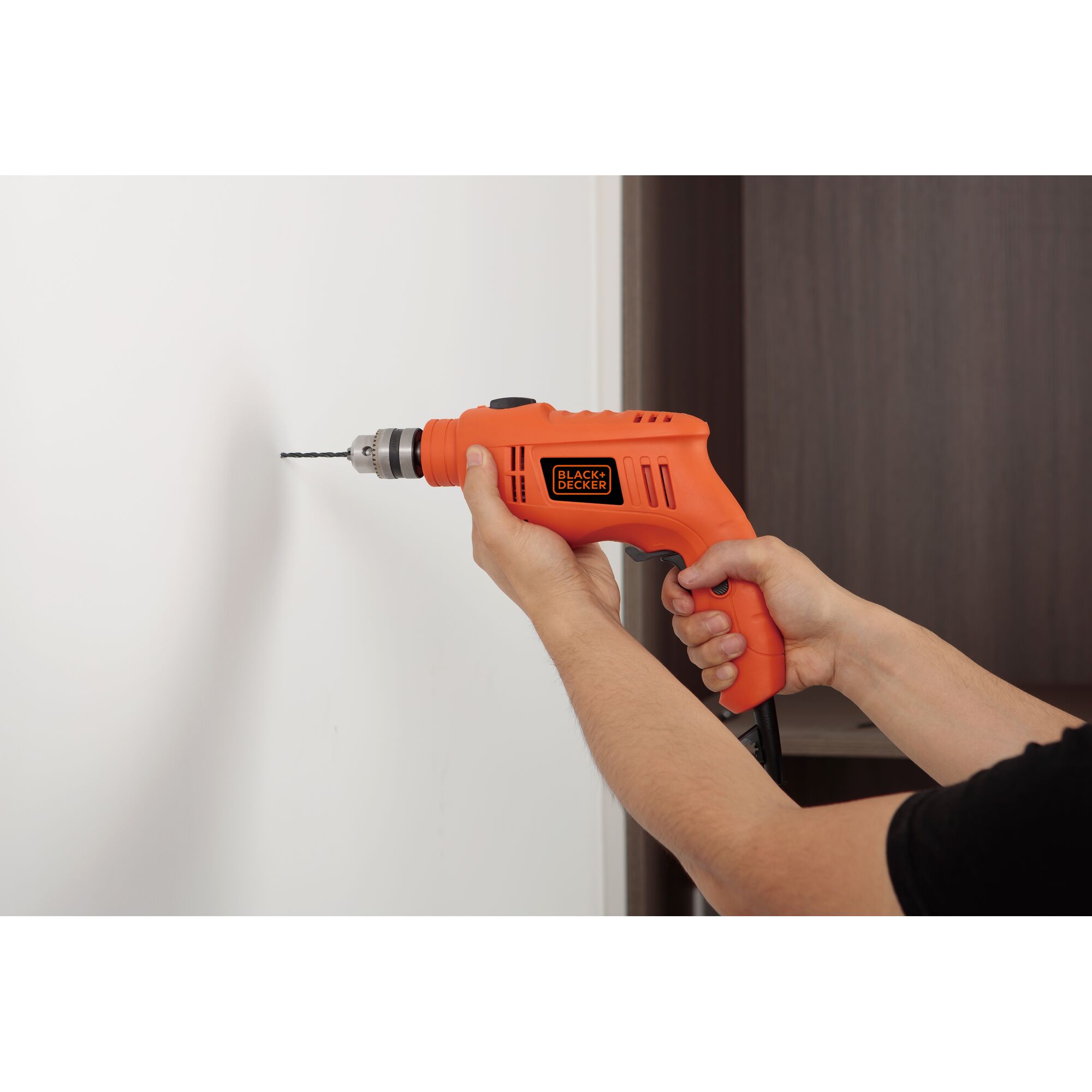 Photo of BLACKDECKER TB555 orange corded drill being used to drill into a white wall.