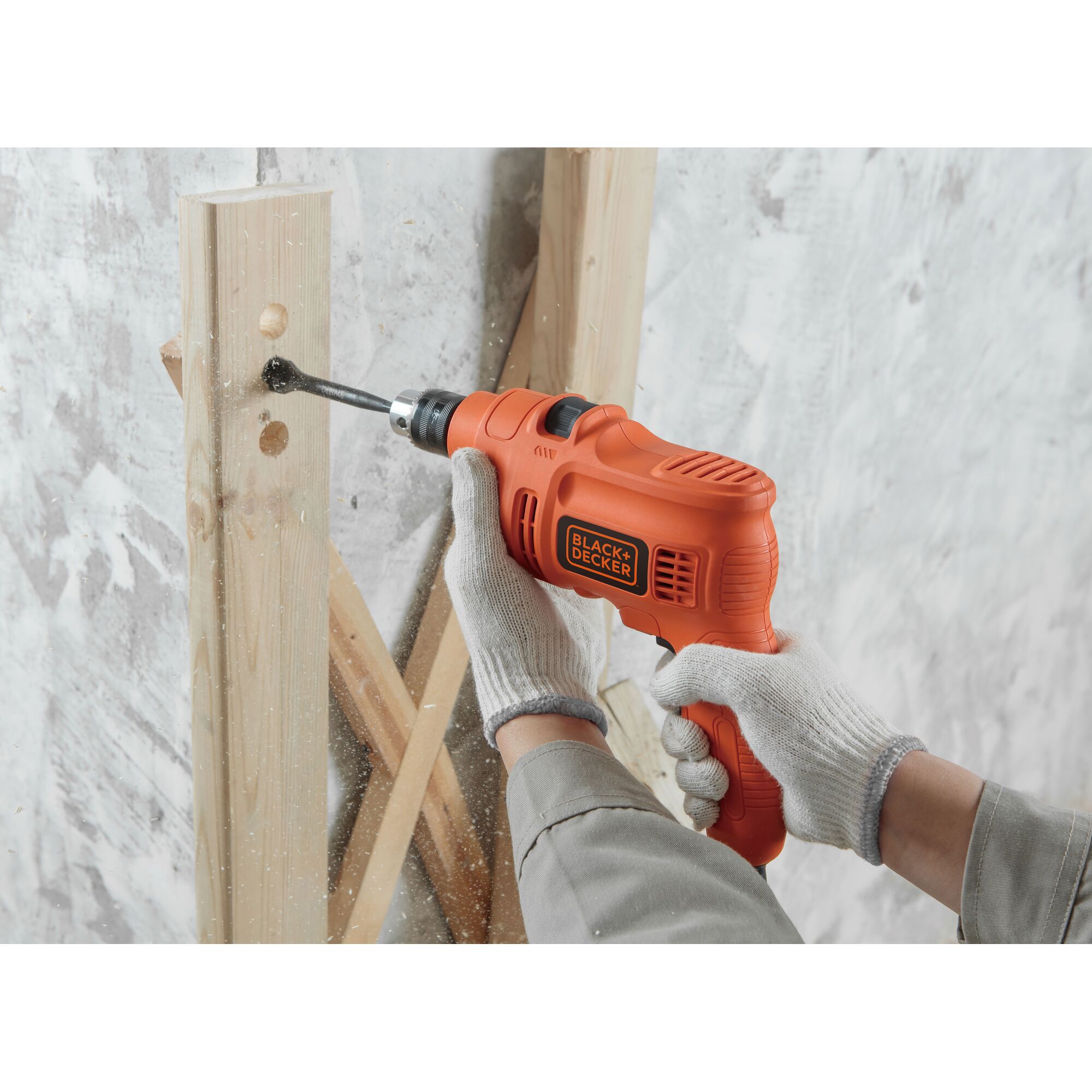 BLACKDECKER TP555KPR orange drill in use drilling wood, close-up photo of tool and gloved hands.