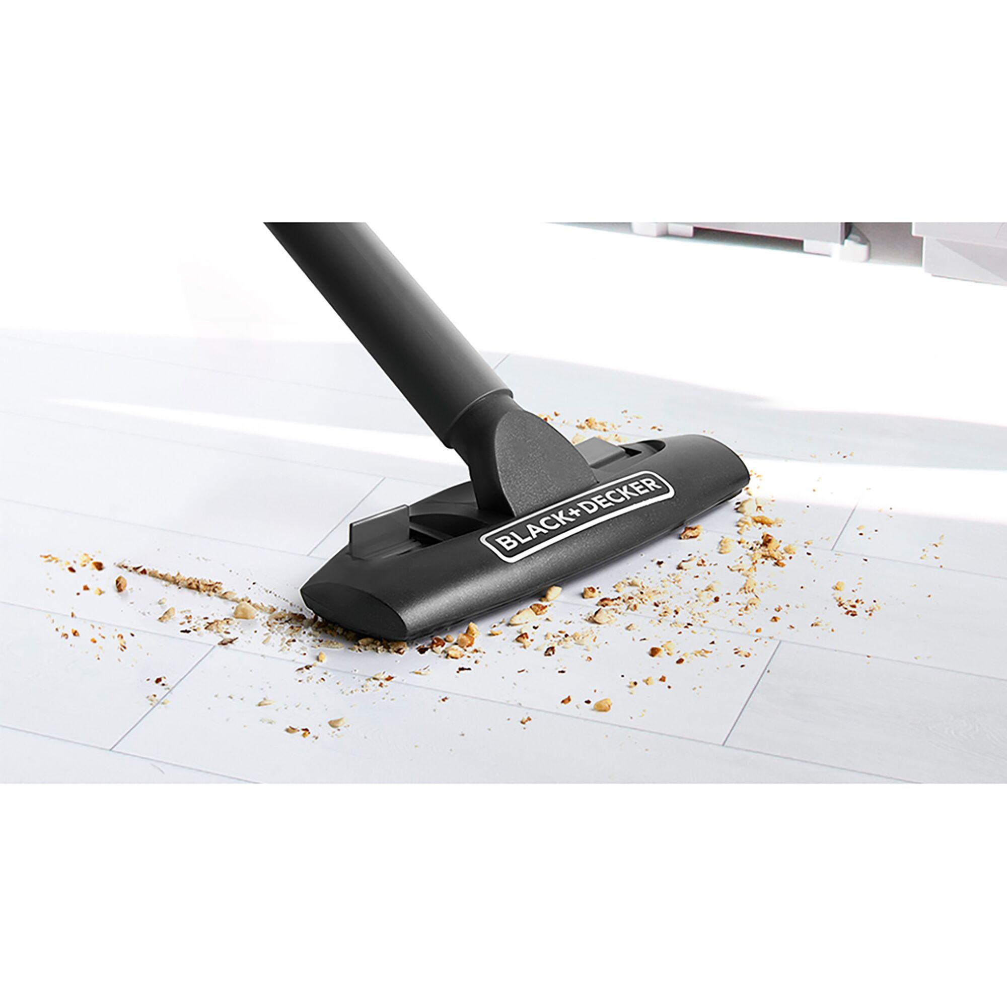 BLACKDECKER vacuum cleaner head TPD1420BK-KR cleaning crumbs on white tile floor, side angle.