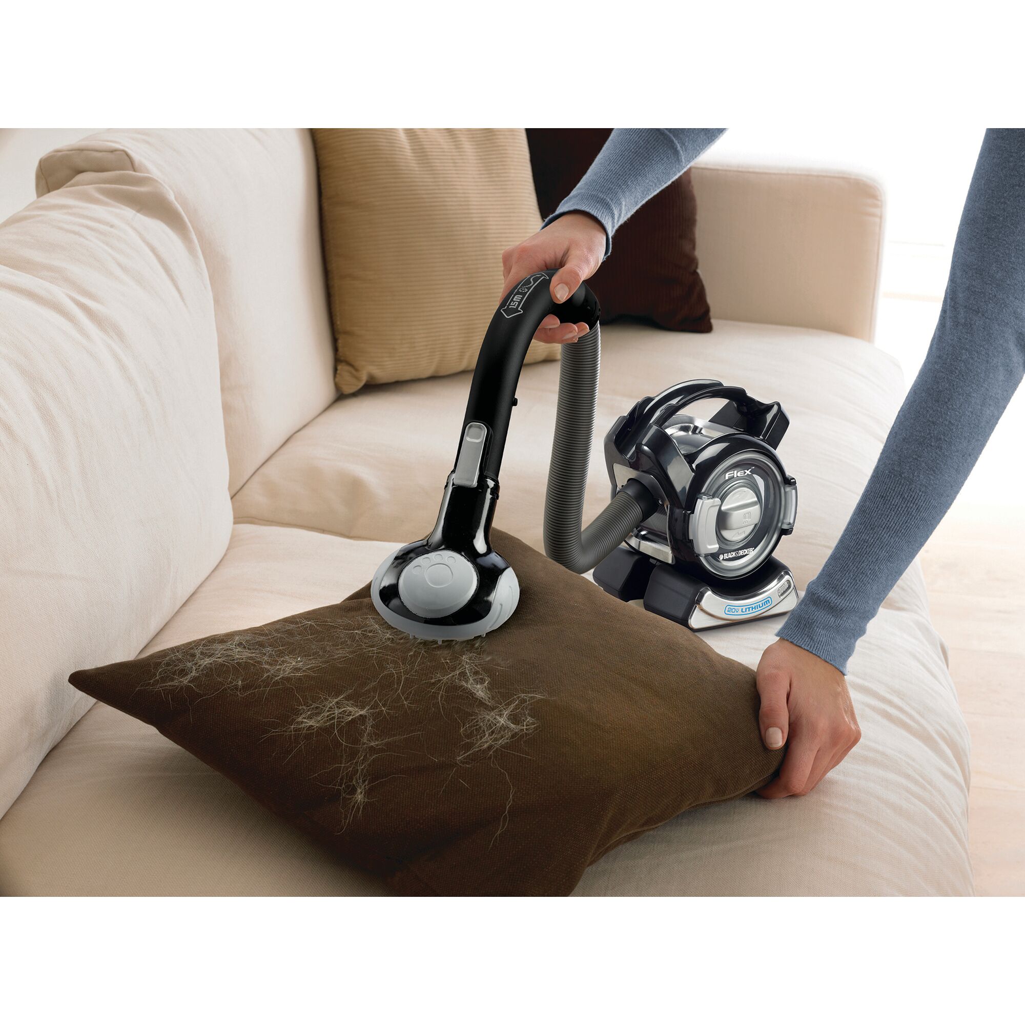 BLACKDECKER TPD1420BOFL vacuum cleaner removing pet hair from pillow on beige sofa, side angle.