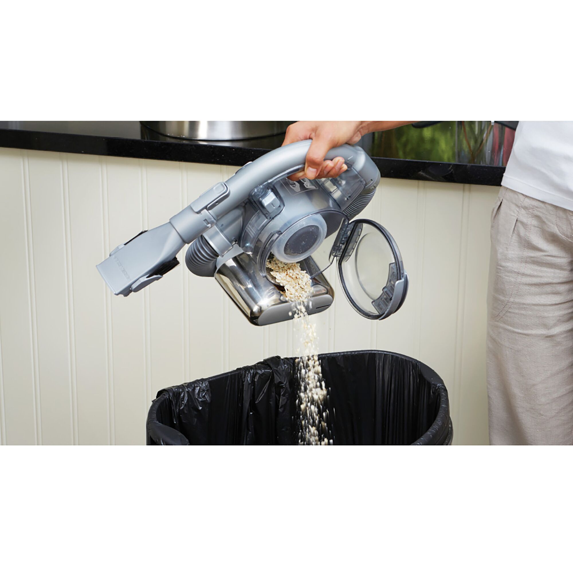 BLACKDECKER TPD1810BGEXT-KR handheld vacuum emptied over trash bin in kitchen, close-up angle.