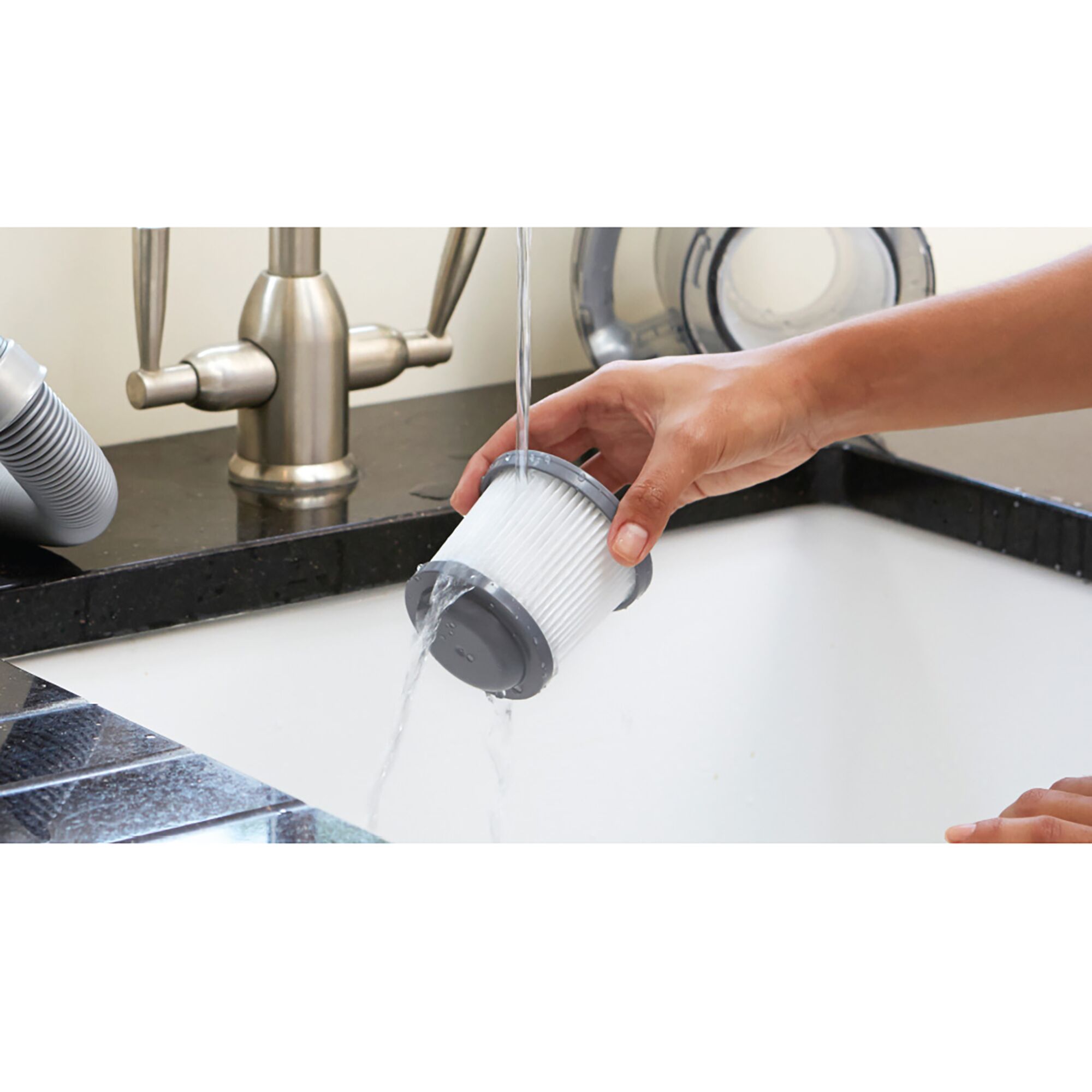BLACKDECKER TPD1810BGEXT-KR filter being rinsed under faucet in kitchen sink, product photography.