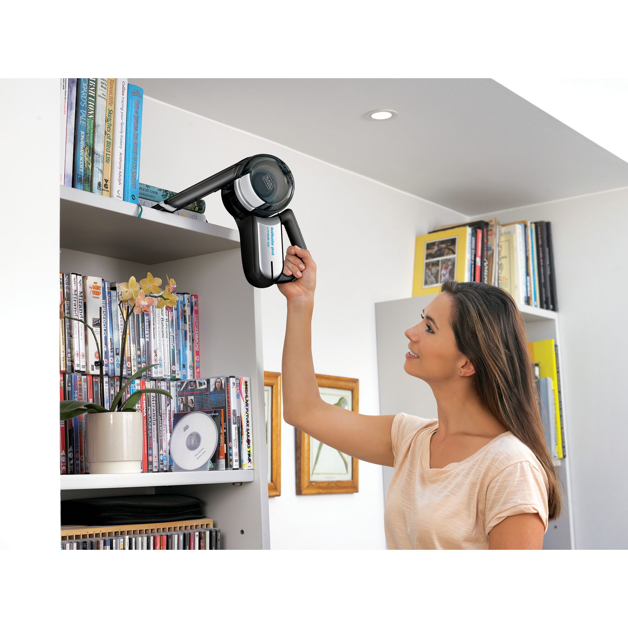 BLACKDECKER TPV1020BOAC handheld vacuum cleaning dust from a bookshelf in a living room setting.