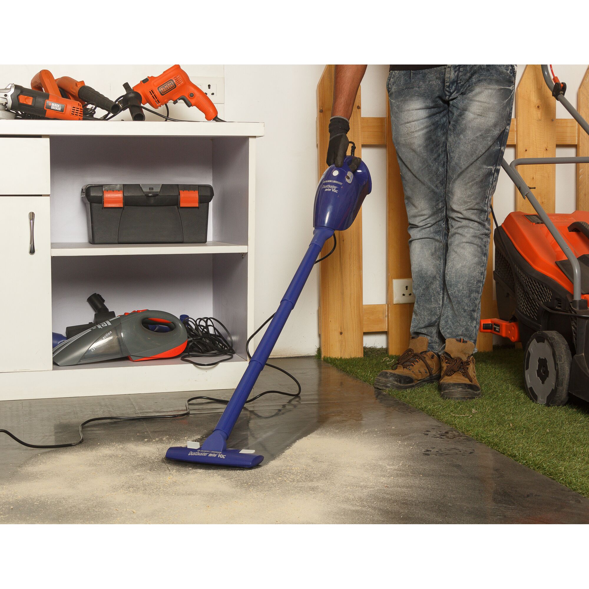 BLACKDECKER VH780 handheld vacuum cleaner, blue, being used on workshop floor, side view.