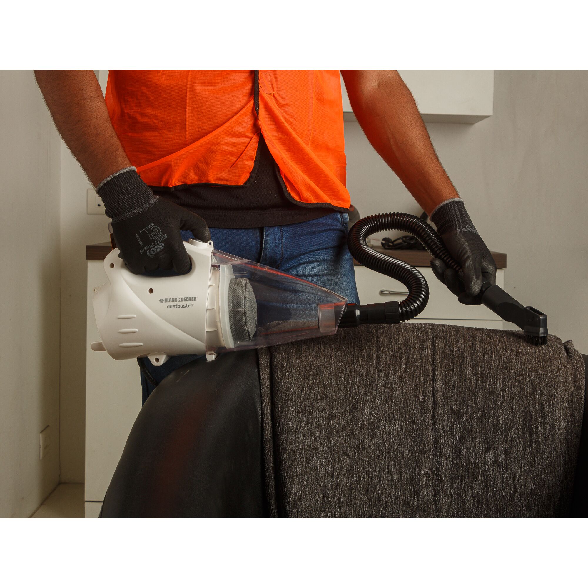 BLACKDECKER VH801 handheld vacuum cleaner used on upholstery with hose attachment.