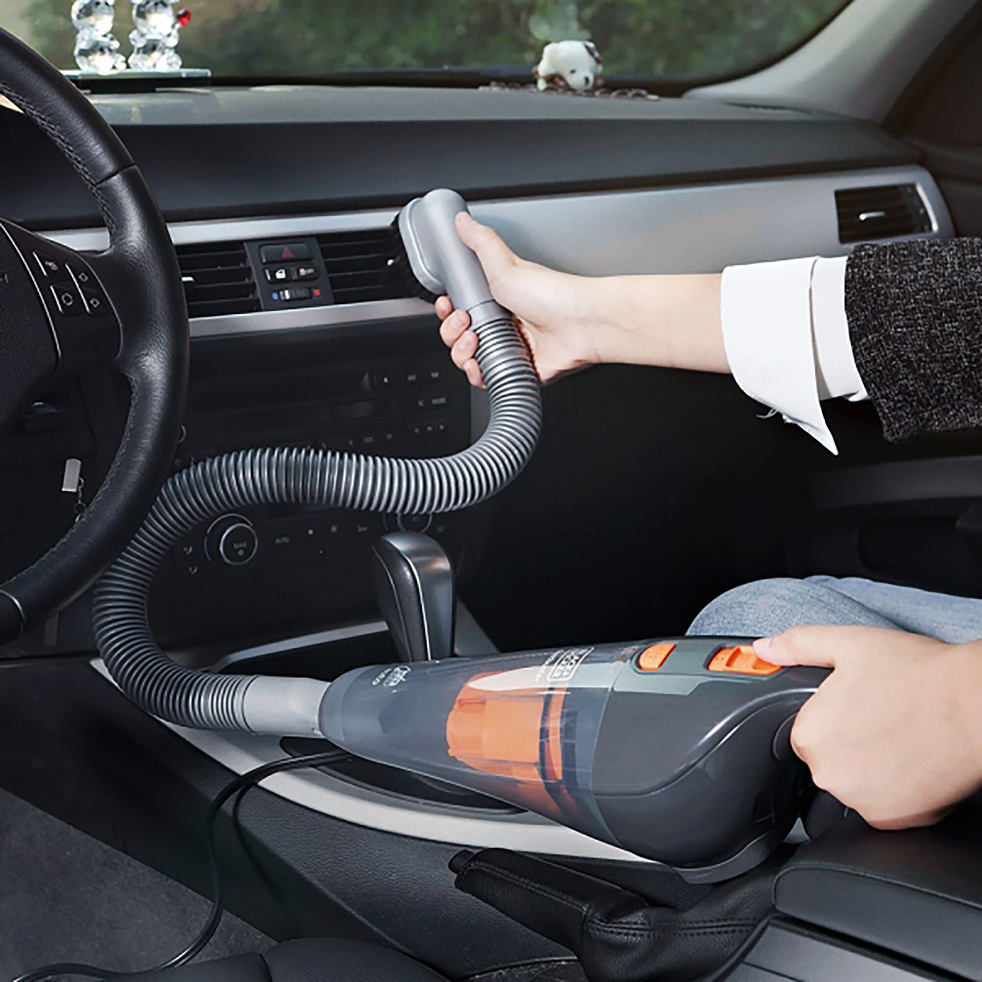 BLACKDECKER WD1210AV handheld car vacuum cleaner with hose attachment in use inside vehicle.
