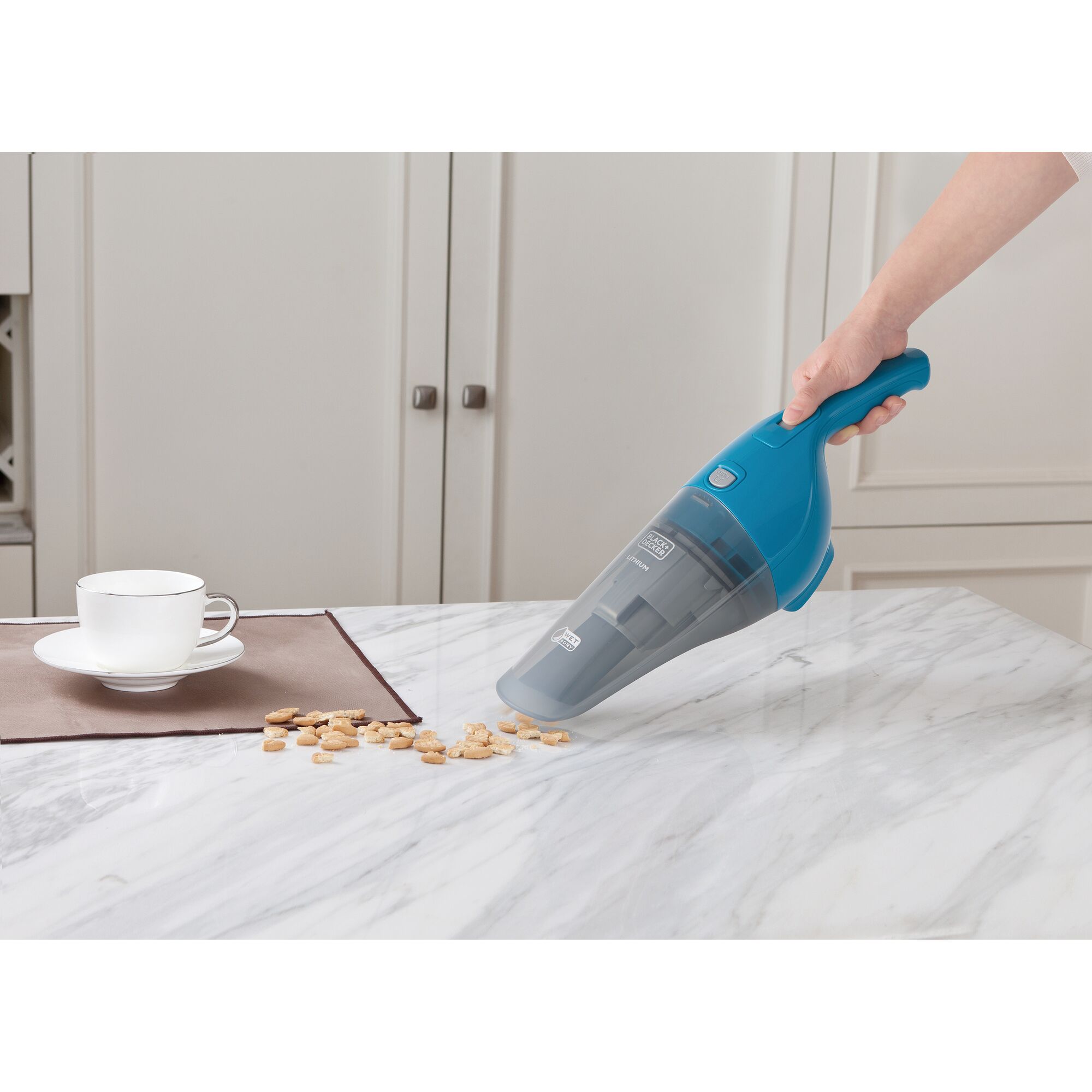 Photo of BLACKDECKER WD7201B handheld vacuum cleaning crumbs from a white marble kitchen countertop.