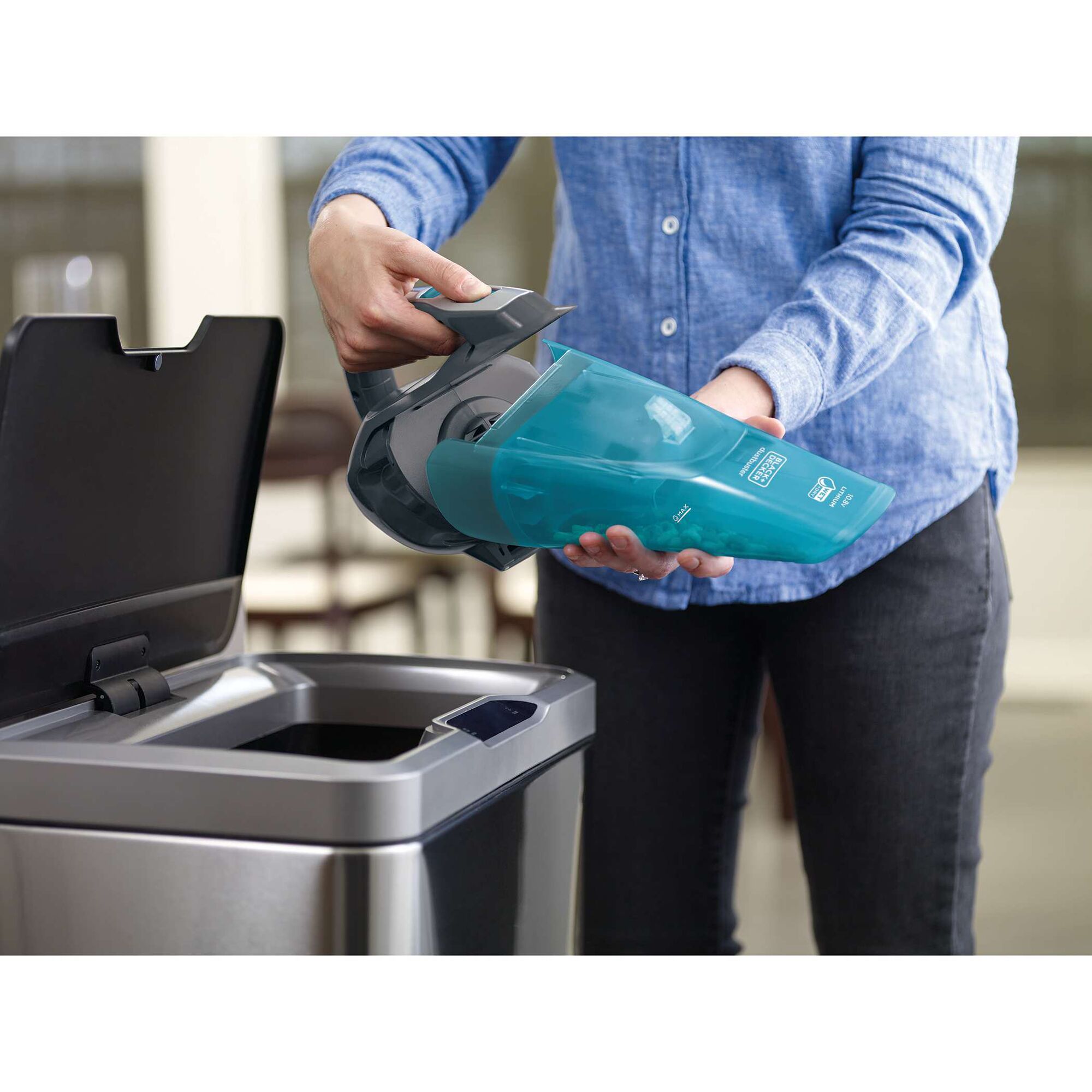BLACKDECKER WDA320B handheld vacuum with blue dustbin being emptied into a trash can.
