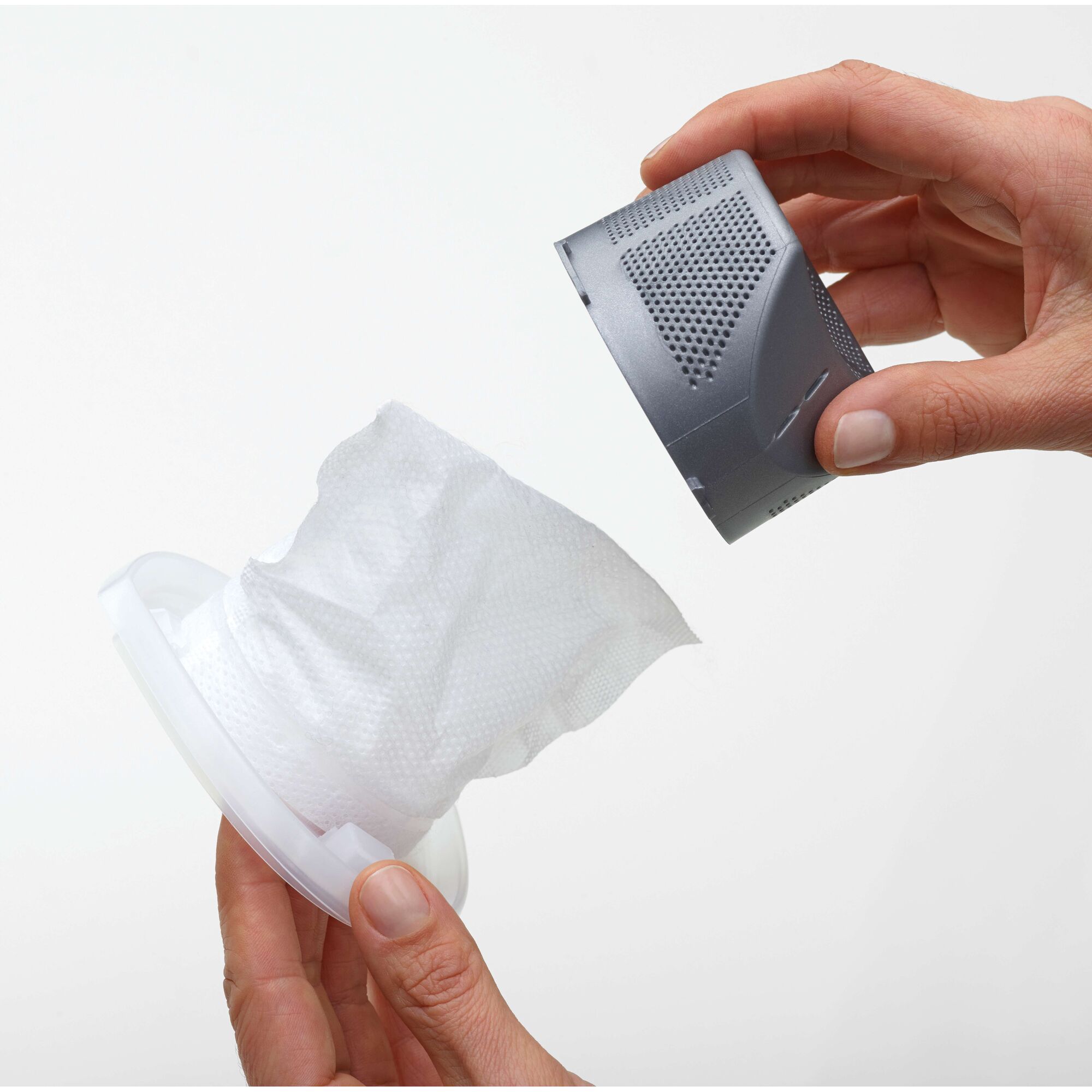 Close-up of two hands holding and separating components of a vacuum cleaner filter, showing the filter element and a plastic part against a plain white background.