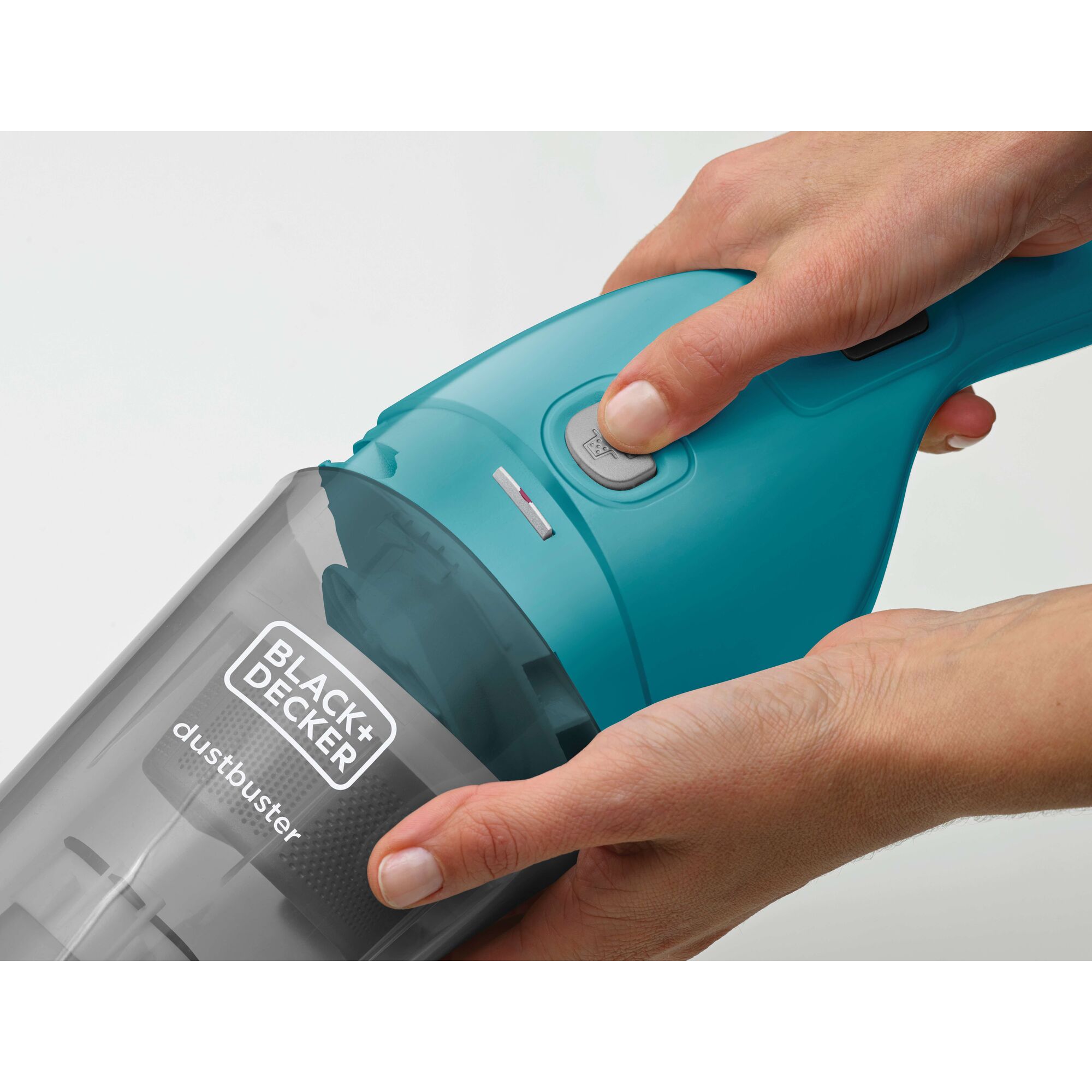 Close-up image of a person holding and pressing the button on a BLACK+DECKER dustbuster handheld vacuum cleaner.