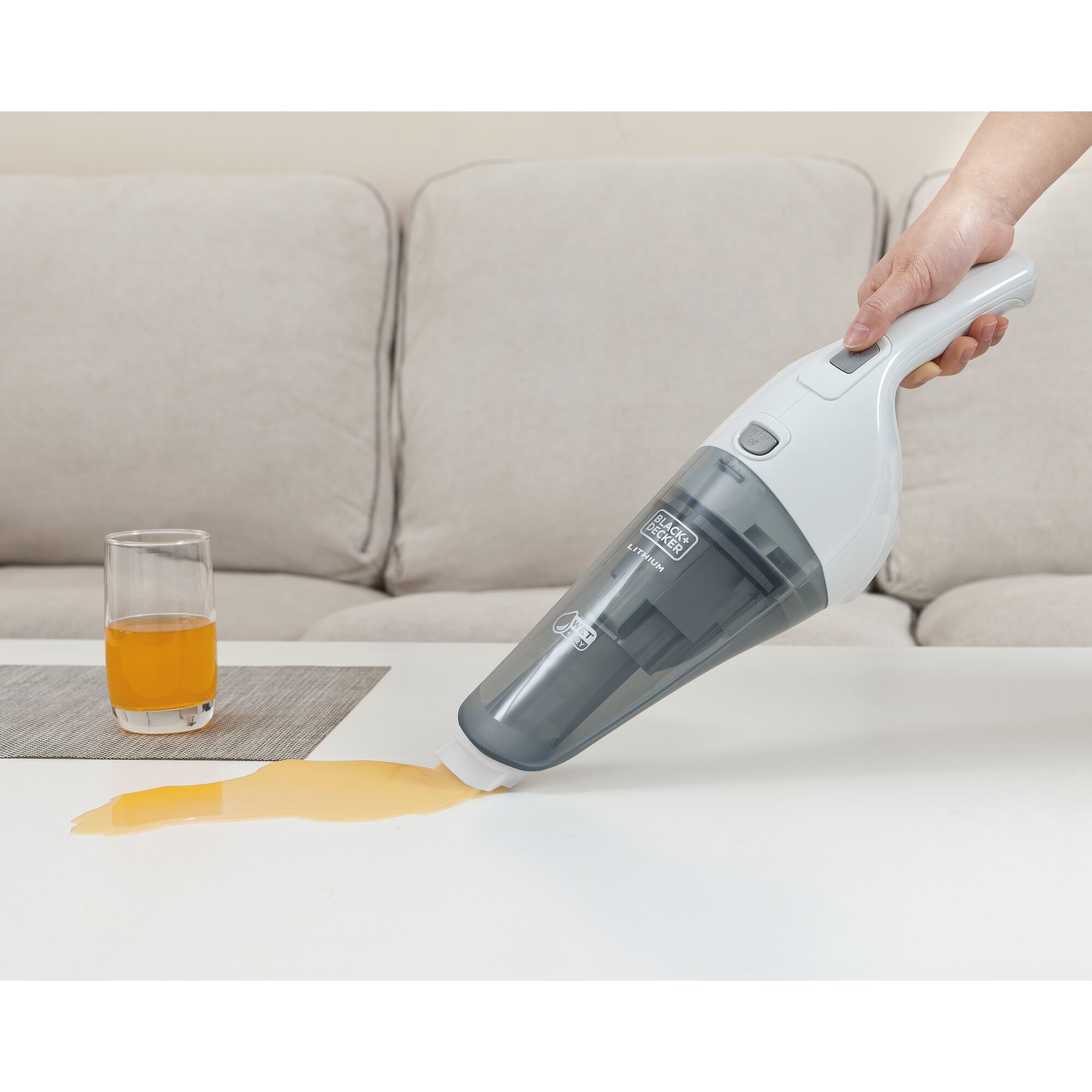 BLACKDECKER WDB115W handheld vacuum cleaning orange juice spill on white table in living room.