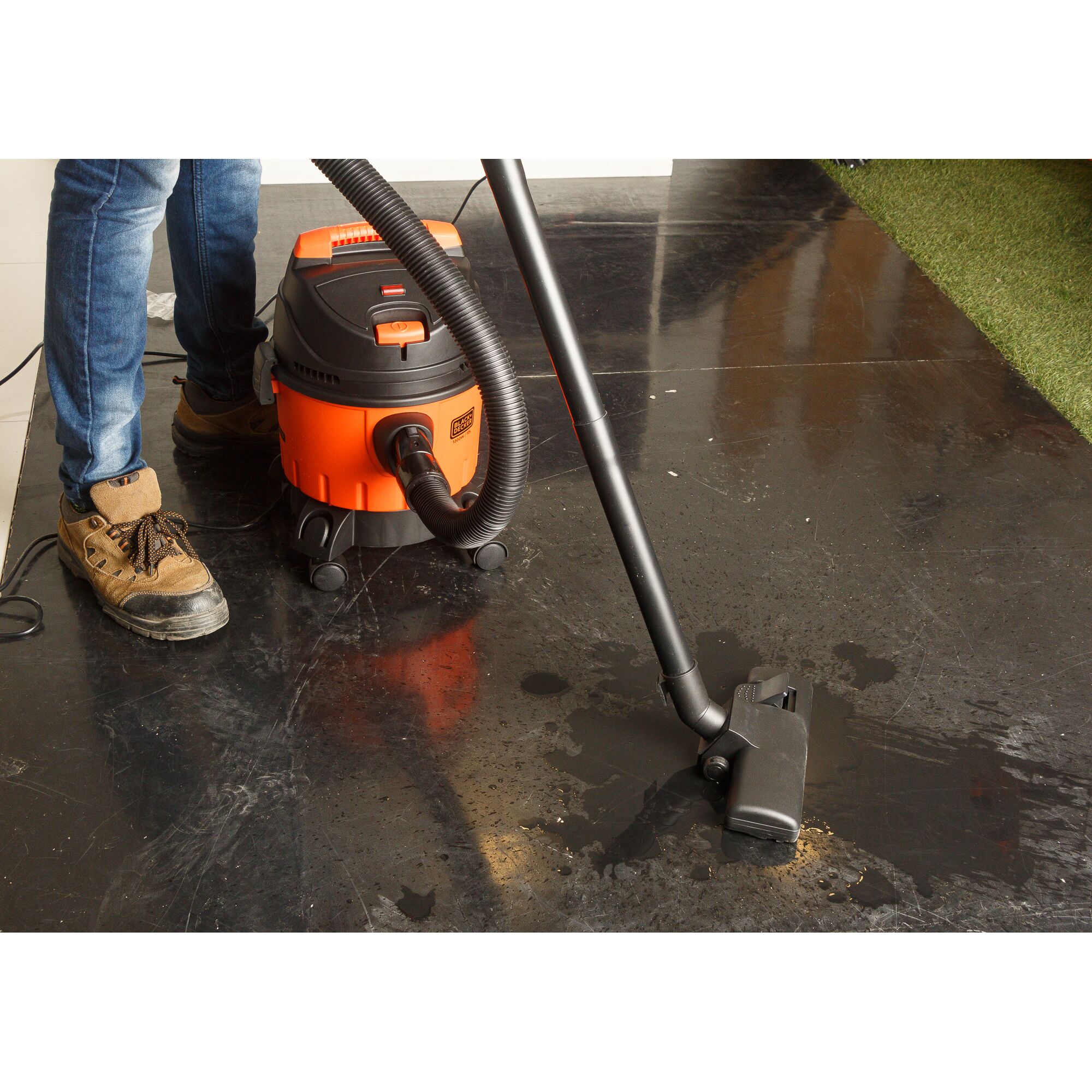 BLACKDECKER WDBD10 wet and dry vacuum cleaner used on a black floor by a person wearing brown shoes.