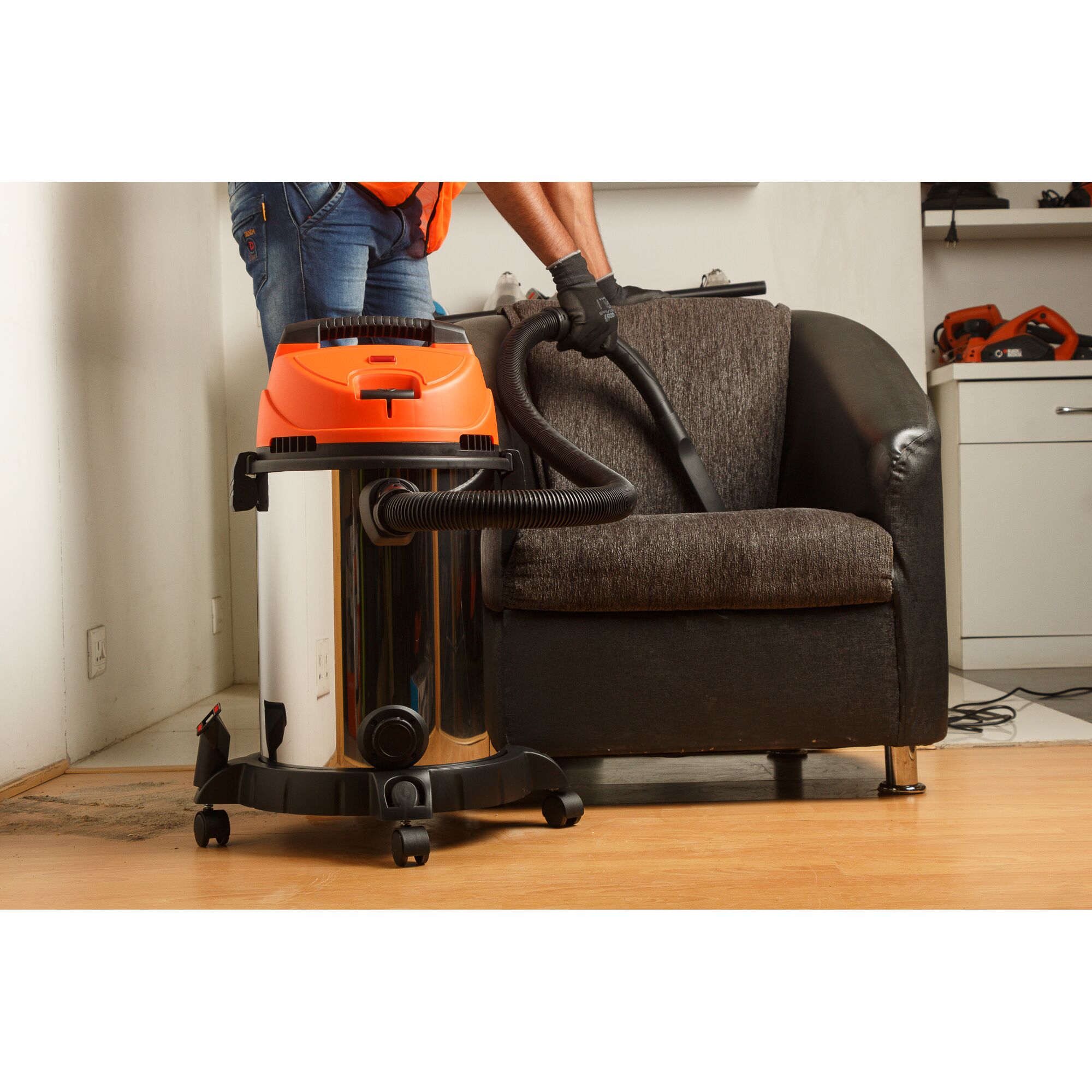 BLACKDECKER WDBDS20 wet and dry vacuum cleaner cleaning a dark fabric armchair in a living room.