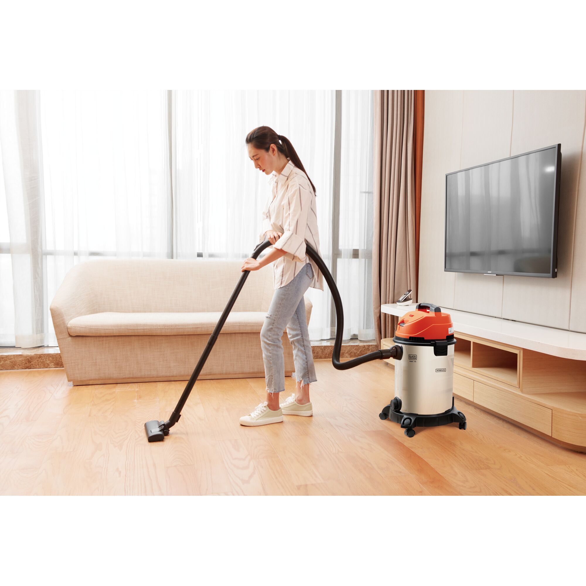 BLACKDECKER WDBDS30 wet and dry vacuum cleaner with orange top used on wooden floor in living room.