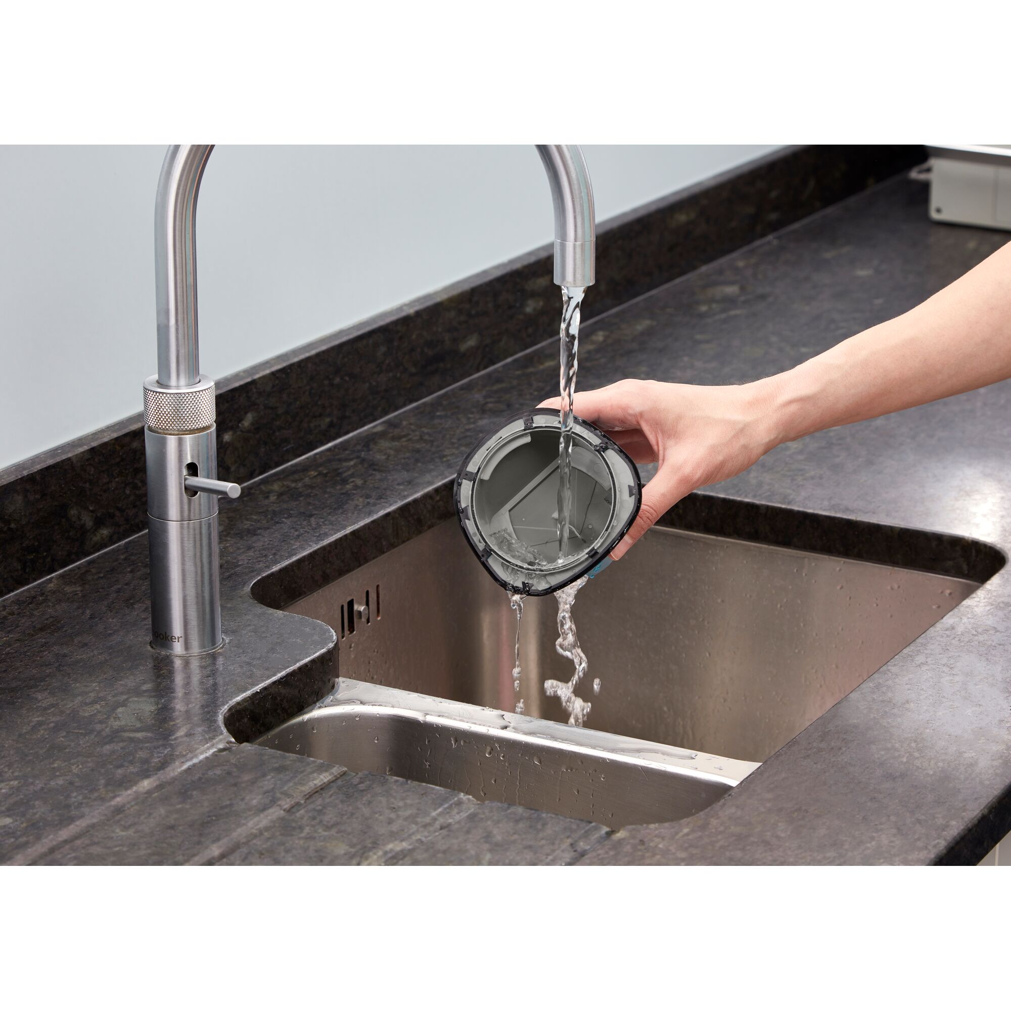 BLACKDECKER WDC115W vacuum filter being rinsed under faucet in kitchen sink.