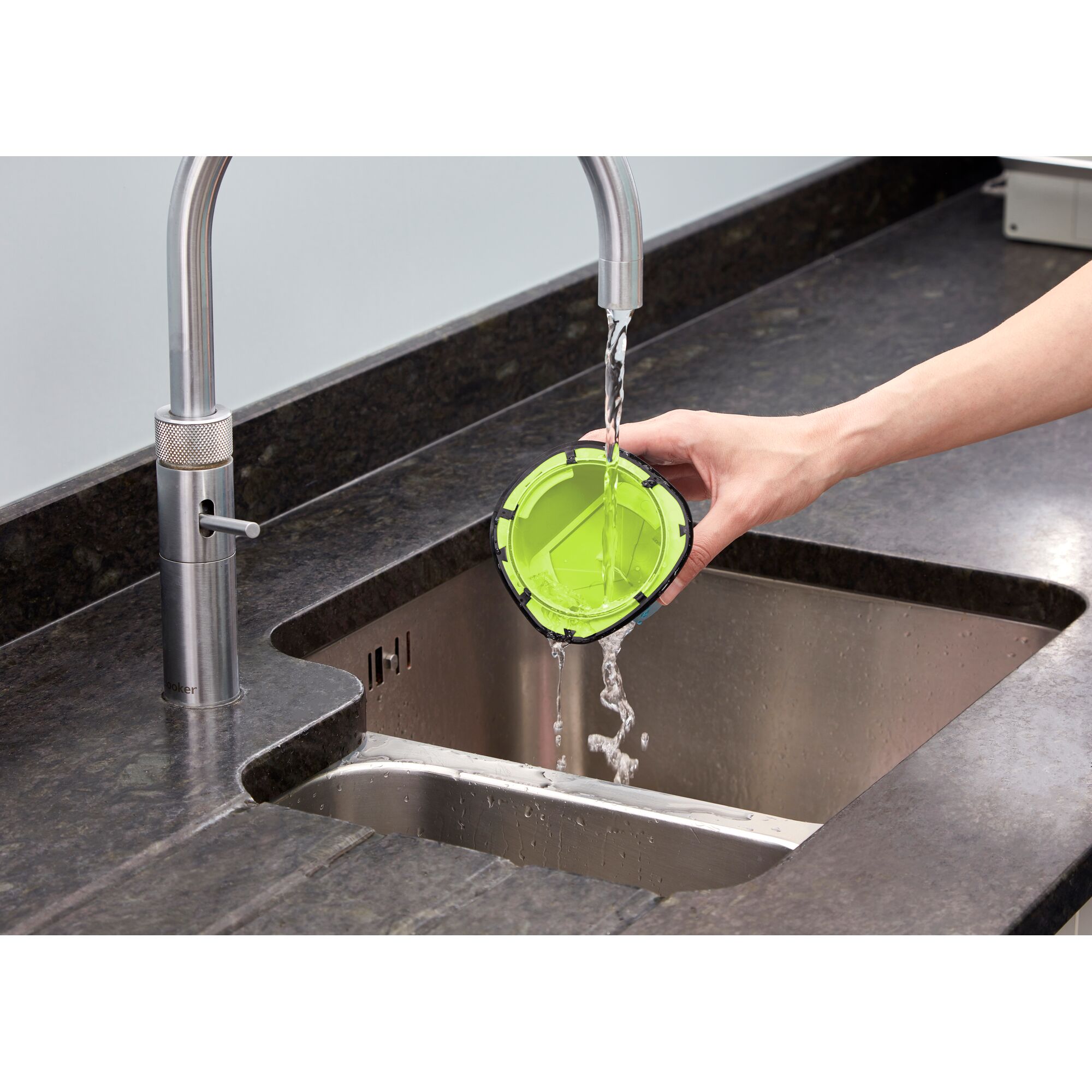 BLACKDECKER WDC215G vacuum filter being rinsed under faucet in kitchen sink.