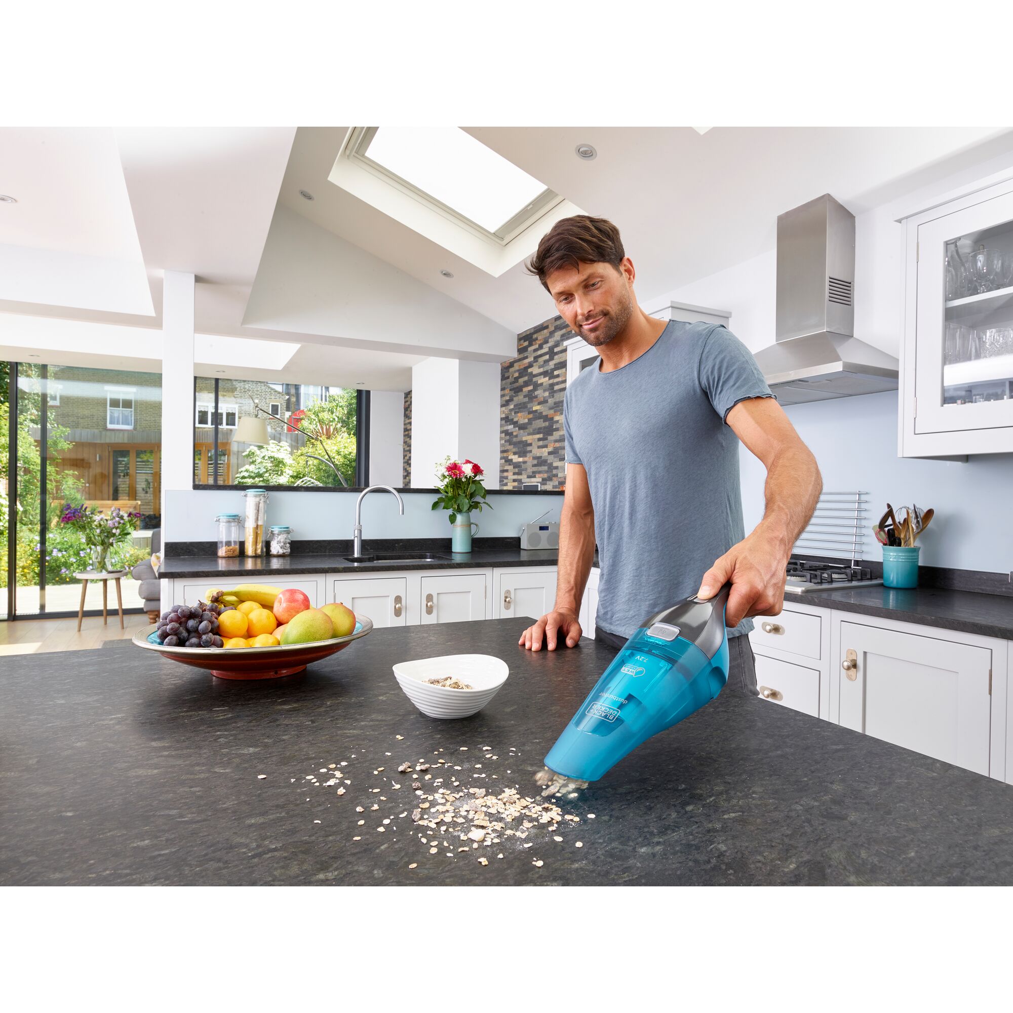 BLACKDECKER WDC215WA handheld vacuum cleaning oats on kitchen counter, fruits and bowl nearby.