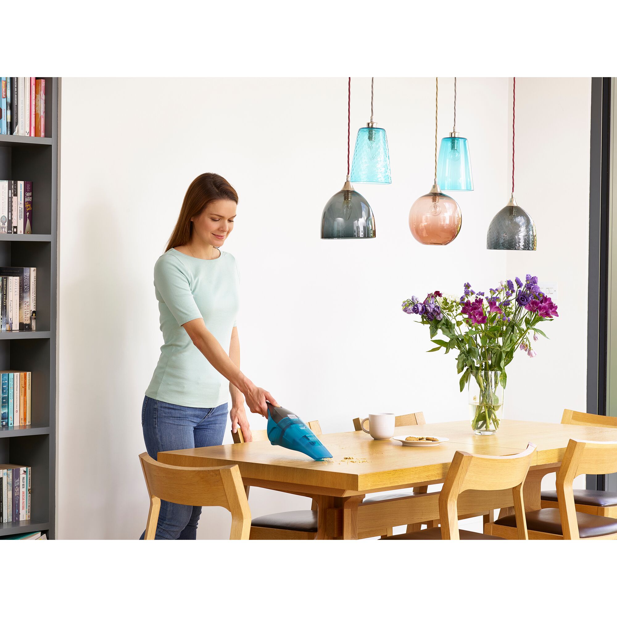 BLACKDECKER WDC215WB handheld vacuum cleaning wooden dining table with crumbs in a modern dining room.