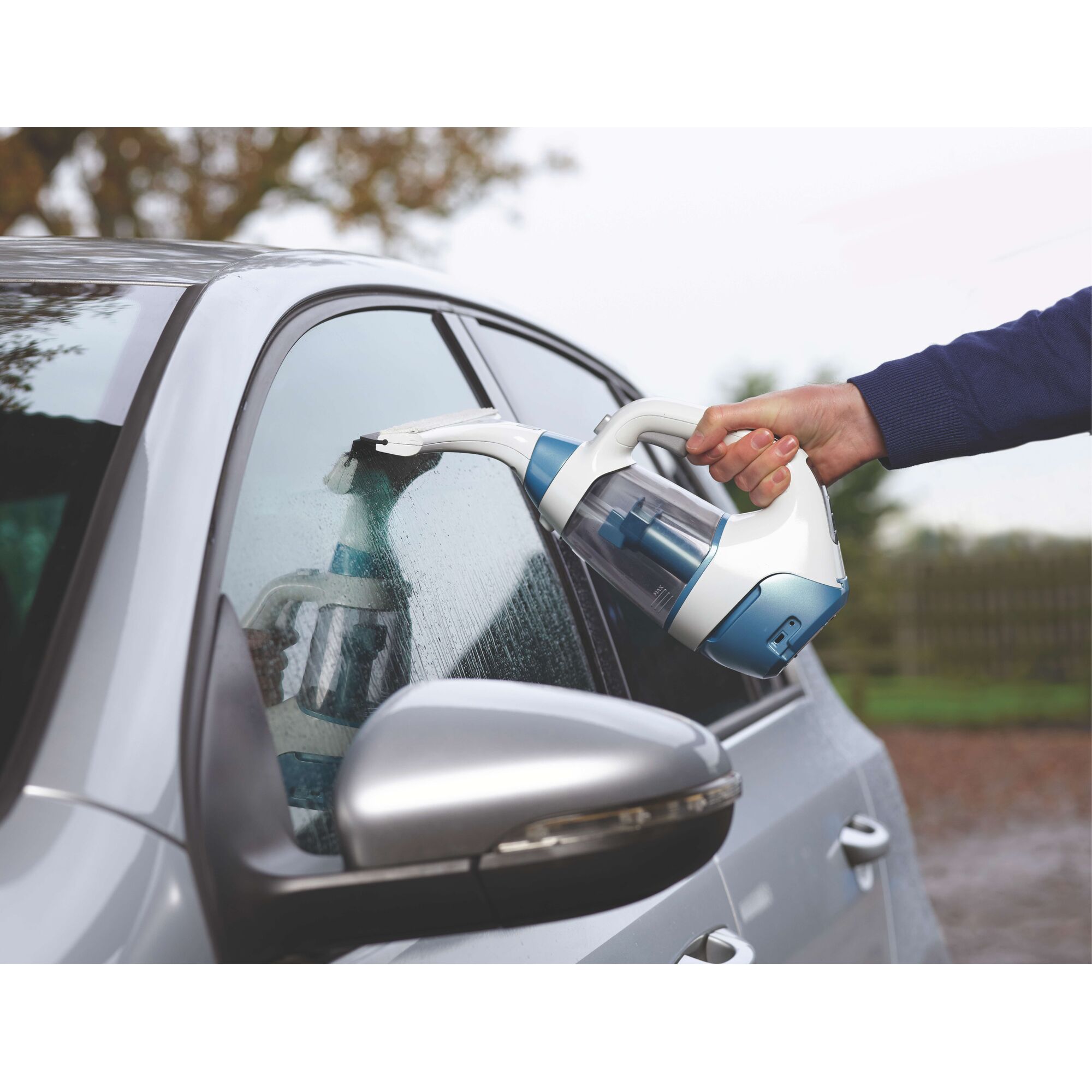 BLACKDECKER WW100 window vacuum cleaner used on a car side window, showing handheld design and blue accents.